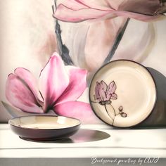 a white bowl with pink flowers on it next to a wallpapered background and plate