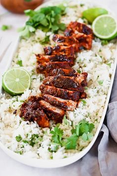 chicken and rice with limes on the side in a white platter, ready to be eaten