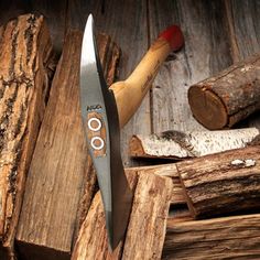 a large knife sitting on top of a pile of wood next to some firewood