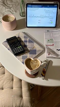 a laptop computer sitting on top of a desk next to a cup of coffee and calculator