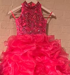 The elegant and sophisticated Sugar Kayne C328 Girls Preteens Pageant Dress boasts a dazzling halter neckline and full ruffle ball gown skirt with a crystal bodice, perfect for making a memorable fashion statement. Be sure to steal hearts in this organza ballgown. Shine like a diamond with the sequin and stones bejeweled bodice and high neck detail, complete with voluminous layers of organza on the skirt. Colors: Barbie Pink, Cinderella Blue, Yellow Sizes: 2, 4, 6, 8, 10, 12, 14, 16 (Sizes 2-6 d Pageant Gown With Ruffles And Fitted Bodice, Pink Sleeveless Pageant Dress For Prom Season, Glamorous Ruffled Ball Gown For Party, Glamorous Ball Gown With Ruffles, Elegant Sleeveless Ball Gown With Ruffles, Ruffled Ball Gown For Pageant, Ruffled Ball Gown Dresses For Pageant, Elegant Ruffled Pageant Dress For Prom Season, Ruffled Ball Gown Dresses For Pageants