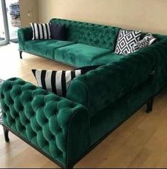 two green couches sitting on top of a hard wood floor next to each other