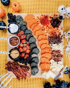 a table topped with lots of halloween food and decorations on top of a yellow blanket