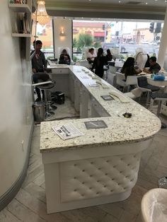 people are sitting at tables in a restaurant with marble counter tops and white stools