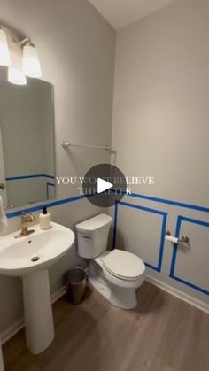 a white toilet sitting next to a sink in a bathroom under blue tape on the walls