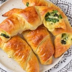 several croissants on a plate with broccoli and cheese in them