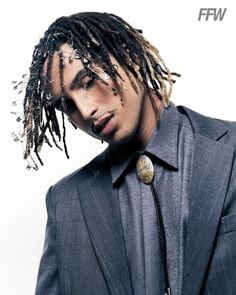 a young man with dreadlocks wearing a suit and tie in front of a white background