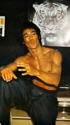 a shirtless man sitting on top of a counter next to a tiger wallpaper