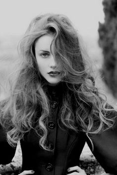 a woman with long hair is posing for a black and white photo, she has her hands on her hips