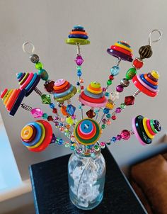 a glass vase filled with lots of colorful beads and pins on top of a table