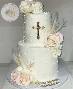 a white wedding cake with flowers and a cross on top