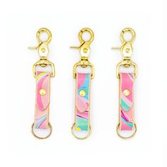 three pieces of pink, yellow and green leather with gold metal clasps on white background