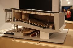 a model of a building with stairs and people standing around it in front of a screen