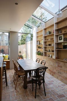 a dining room table and chairs in front of an open glass wall with shelves on both sides