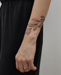 a woman's arm with a leaf tattoo on the left side of her wrist