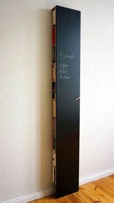 a tall book shelf with books on it in front of a white wall and wooden floor