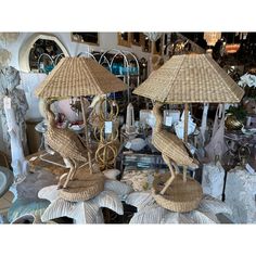 two wicker umbrellas with birds on them sitting on top of shells in a store