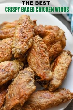 chicken wings on a white plate next to broccoli and lettuce leaves