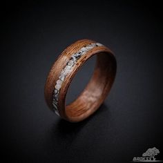 a wooden ring with silver and wood inlays on the inside, sitting on a black surface