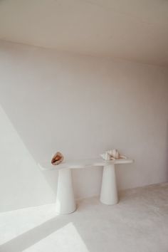 two white pedestals with seashells on them against a white wall in a room