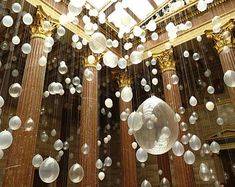 some white balls are floating in the air above a large room with columns and pillars