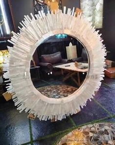 a round mirror sitting on top of a tiled floor next to a table and chair