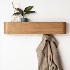 a wooden shelf with a plant on it and a scarf hanging from the wall next to it