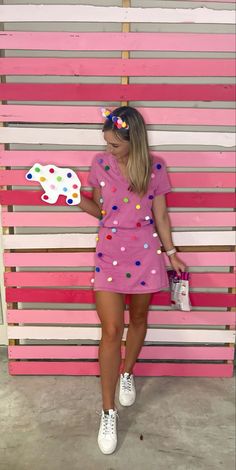 a woman standing in front of a pink and white wall with polka dots on it