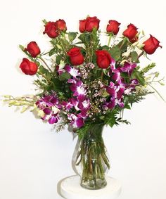 a vase filled with lots of purple and red flowers on top of a white table