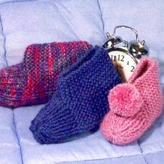 three knitted slippers and an alarm clock are sitting on a blue couch cushion