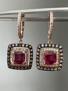 "Offered here is a beautiful pair off earrings with chocolate and vanilla diamonds set in rose gold that feature a treated ruby. This set would make a great gift to surprise a loved one or add this stunning pair to your own collection. The sparkle on these is so gorgeous-especially in the sunlight, that's when they really light up! These earrings always get compliments!  The earrings feature a treated ruby in a halo of sparking diamonds set in 14k rose gold. These are stamped 14k on the posts al Rose Gold Diamond Earrings With Gemstone, Luxury Red Diamond Earrings As Gift, Luxury Red Diamond Earrings For Gift, Red Luxury Diamond Earrings As Gift, Luxury Ruby Earrings With Halo Design, Rose Gold Ruby Jewelry With Diamond Accents, Exquisite Rose Gold Ruby Jewelry, Rose Gold Earrings With Single Cut Diamonds, Red Ruby Earrings With Diamond Accents