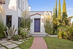 a white house with a blue door and brick walkway leading to it's front entrance