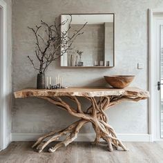 a wooden table with a bowl on top of it next to a mirror and vase