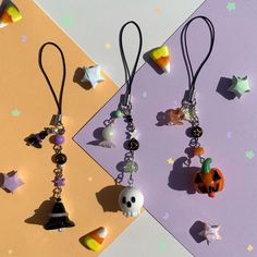 three halloween themed items are hanging from earwires on a purple and yellow background