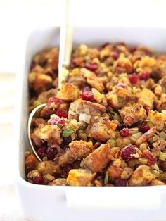 a white dish filled with stuffing and cranberries