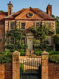 a large brick house with an iron gate and ivy covered trees on the front door