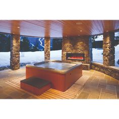 an outdoor hot tub in the middle of a patio with snow on the ground and rocks around it