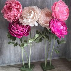 three vases with flowers in them sitting on a table next to a wall and floor