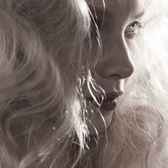 a woman with long blonde hair is looking at another woman's face in black and white