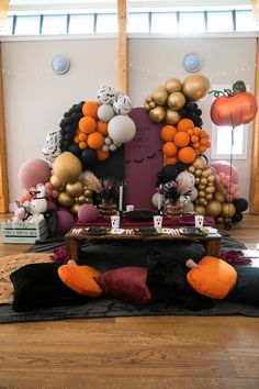 a table topped with lots of balloons on top of a wooden floor next to a wall