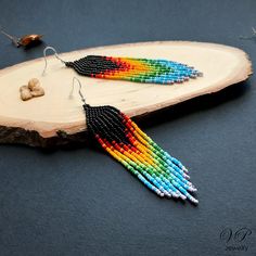 a pair of multicolored beaded earrings sitting on top of a piece of wood