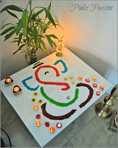 a decorated table with candles and a potted plant in the corner next to it