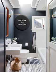 a white toilet sitting next to a bathroom sink under a window in a blue wall