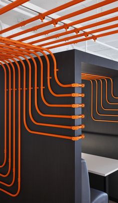 an office cubicle with orange piping on the ceiling