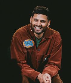 a man sitting down with a doughnut on his lap and smiling at the camera