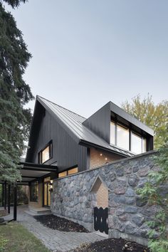 the house is made out of black wood and has a stone walkway leading up to it