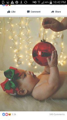 a baby laying on its back with a christmas ornament hanging from it's head