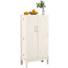 a white cabinet with oranges on top and a vase sitting on top of it