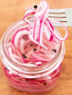 a fork sticking out of a jar filled with pickled onions