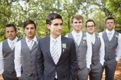 a group of men standing next to each other wearing suits and ties with trees in the background